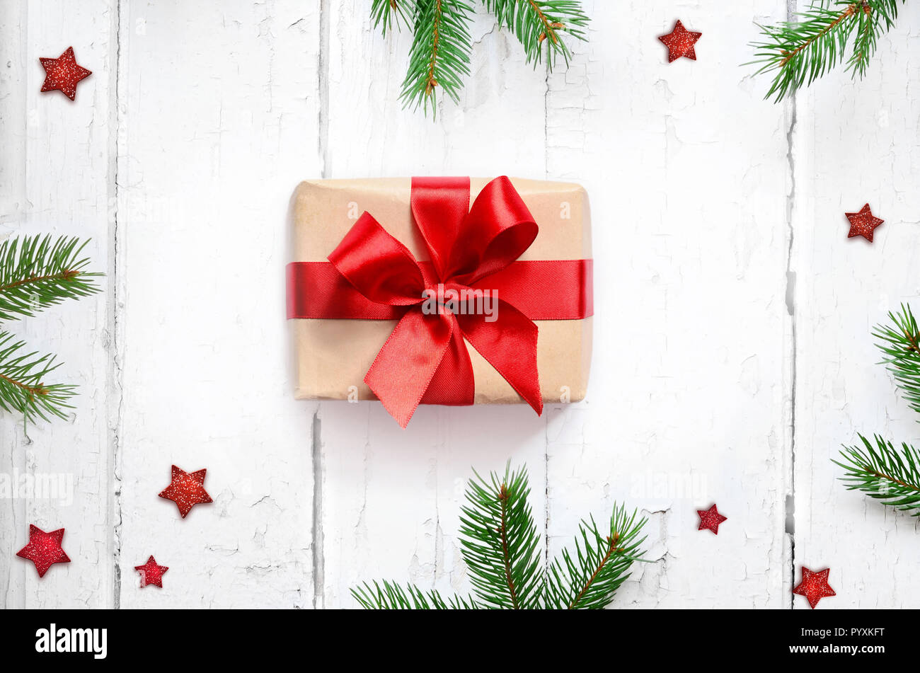 Confezione regalo con nastro rosso su uno sfondo di legno con rami di pino. Vista dall'alto. Foto Stock