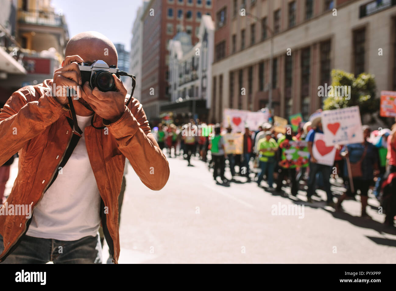 Un fotografo professionista che consente di scattare fotografie con la fotocamera digitale di attivisti segni di contenimento con gli slogan sulla strada della citta'. L'uomo scattare foto del rally di Foto Stock