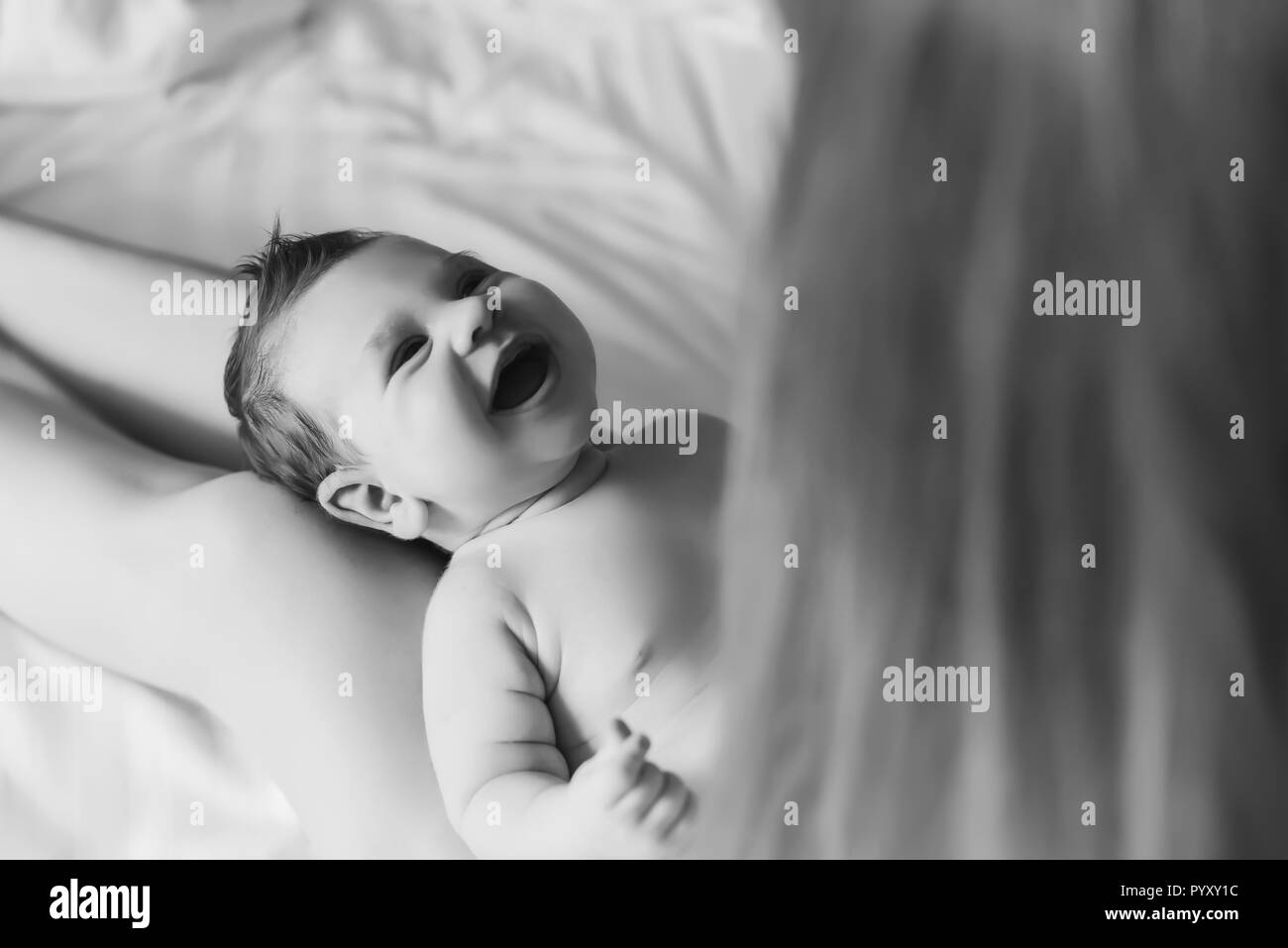 Vista parziale di donna giocando con poco sorridente baby boy nel letto di casa Foto Stock