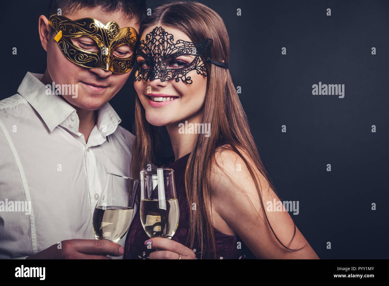 Coppia giovane per celebrare il capodanno bevendo champagne su masquerade party Foto Stock