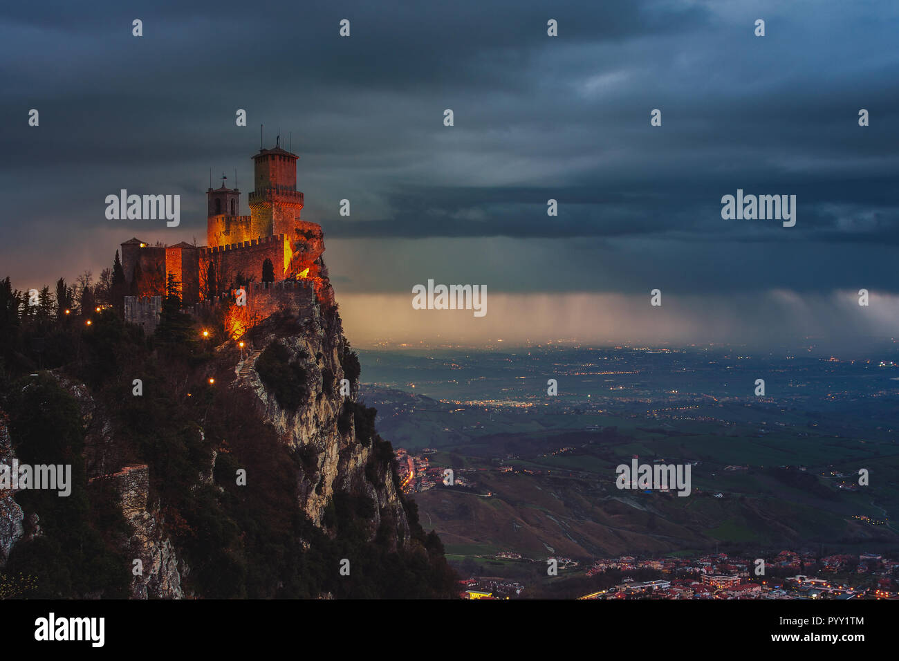 San Marino rocca di Guaita sul Monte Titano al tramonto. Pioggia pesante di nuvole con vista aerea alla città. Auto semafori e illuminazione Foto Stock