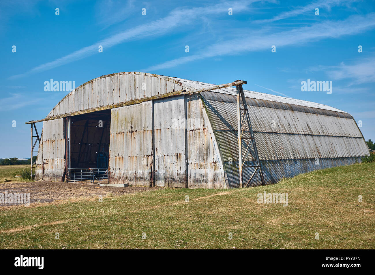 Una vecchia ruggine in disuso hangar aereo ora adibita a fienile in un agriturismo Foto Stock