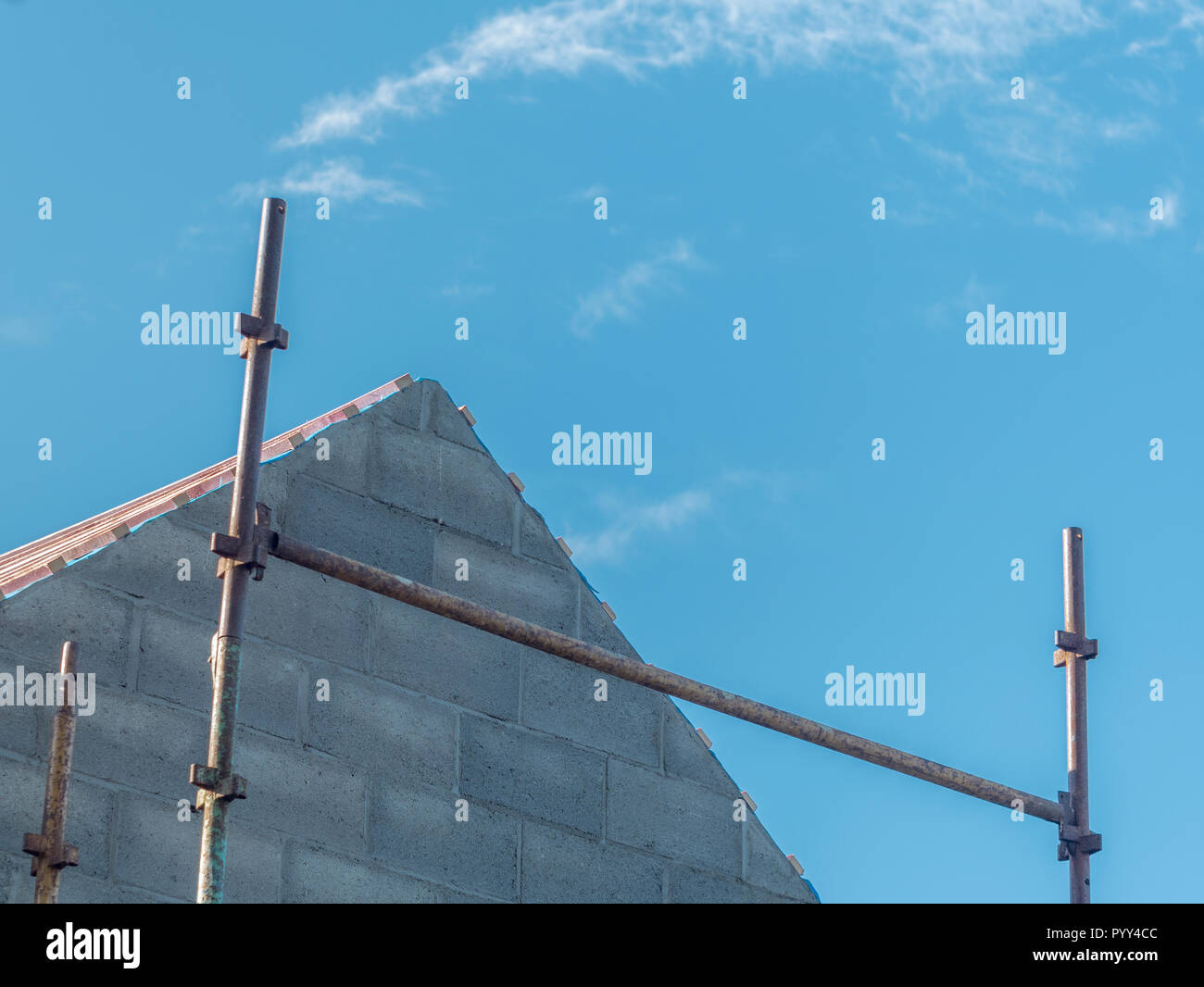 Estremità timpano di una casa nuova-costruzione con impalcatura visibile. Contro il cielo blu. Per il settore edile del Regno Unito. Foto Stock