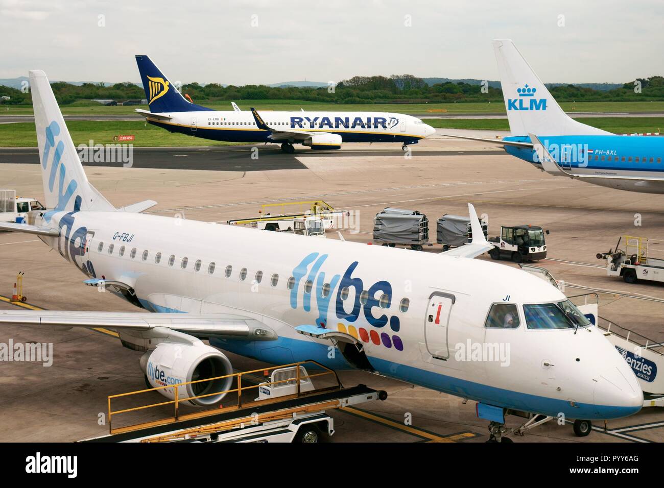 Flybe, Ryanair e KLM aereo passeggeri aerei jet aereo sulla pista grembiule visto da cancelli d'imbarco di Manchester Airport Terminal, Inghilterra Foto Stock