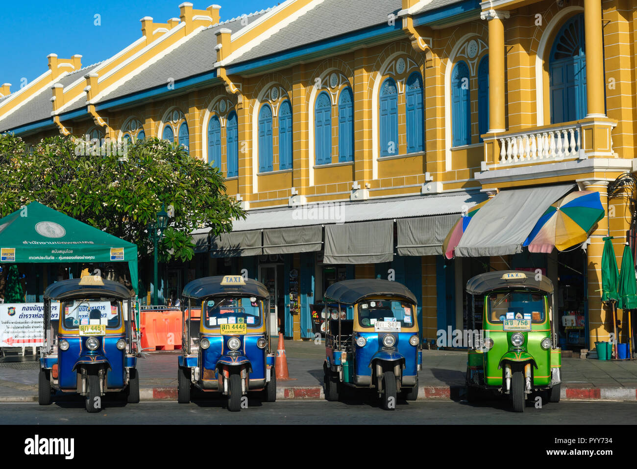Tre ruote di taxi, cosiddetta di tuk-tuks, a fronte di un edificio di stile coloniale in uno di Bangkok aree turistiche, Thailandia, in attesa per i passeggeri Foto Stock
