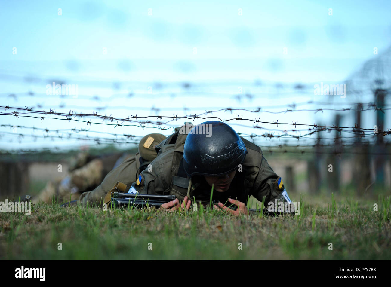 Su una formazione militare di massa, esercizi: soldato ucraino di strisciare sotto fili spinati. Ottobre 18, 2018. Novo-Petrivtsi, Ucraina Foto Stock