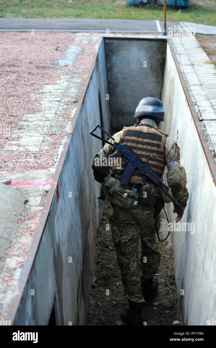 Su una formazione militare di massa, ostacolo corso: soldier strisciando fuori di una trincea. Ottobre 18, 2018. Novo-Petrivtsi base militare, Ucraina Foto Stock