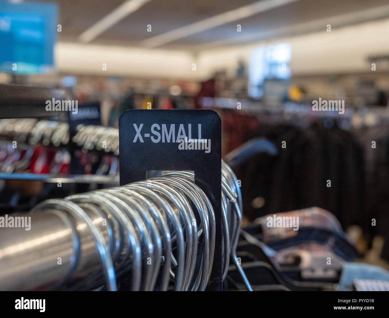 X-small extra small vestiti sezione segno su acciaio hanging rack con staffe in department store Foto Stock