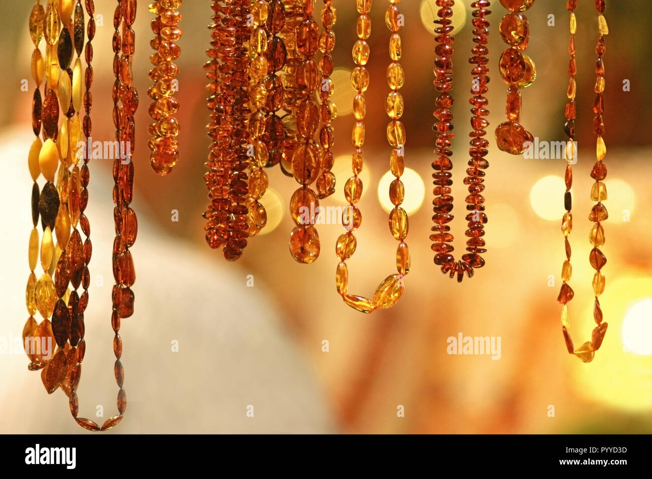 Fila di color oro collane ambra appeso di fronte a uno sfondo luminoso con  luci Foto stock - Alamy
