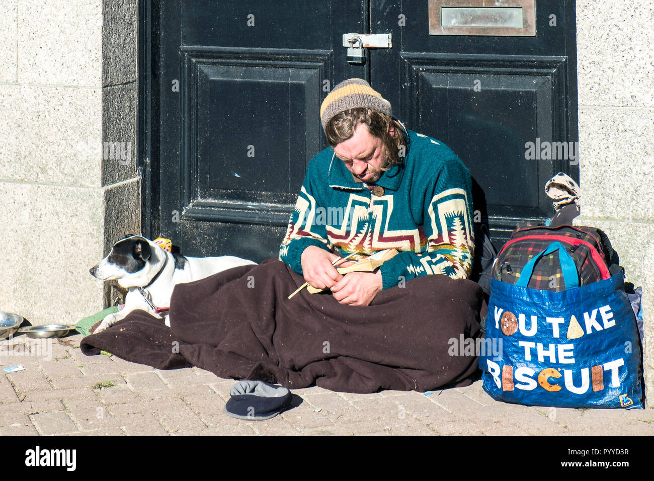 Un senzatetto e il suo cane seduto in una porta. Foto Stock