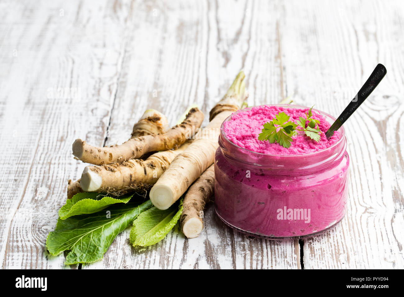 Piccante salsa di rafano in piccolo vasetto di vetro sul tavolo di legno Foto Stock