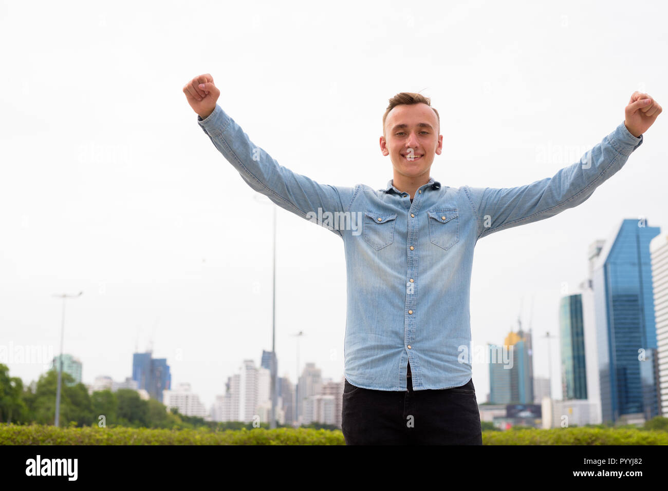 Giovane uomo bello con le braccia sollevate all'aperto Foto Stock