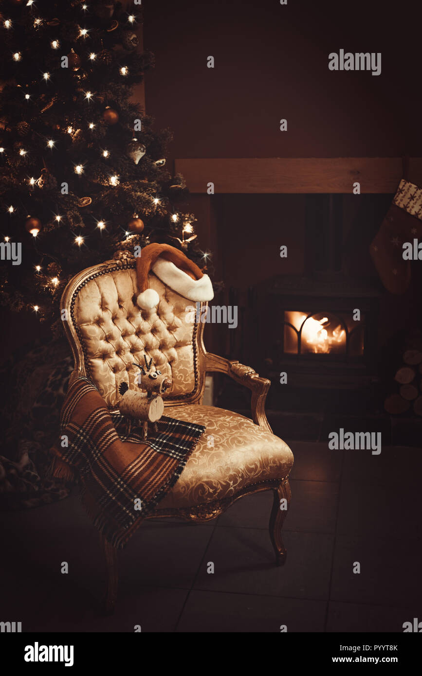 Festa della vigilia di Natale da uno scoppiettante fuoco di legna e renne ornamento sulla coperta di tartan Foto Stock
