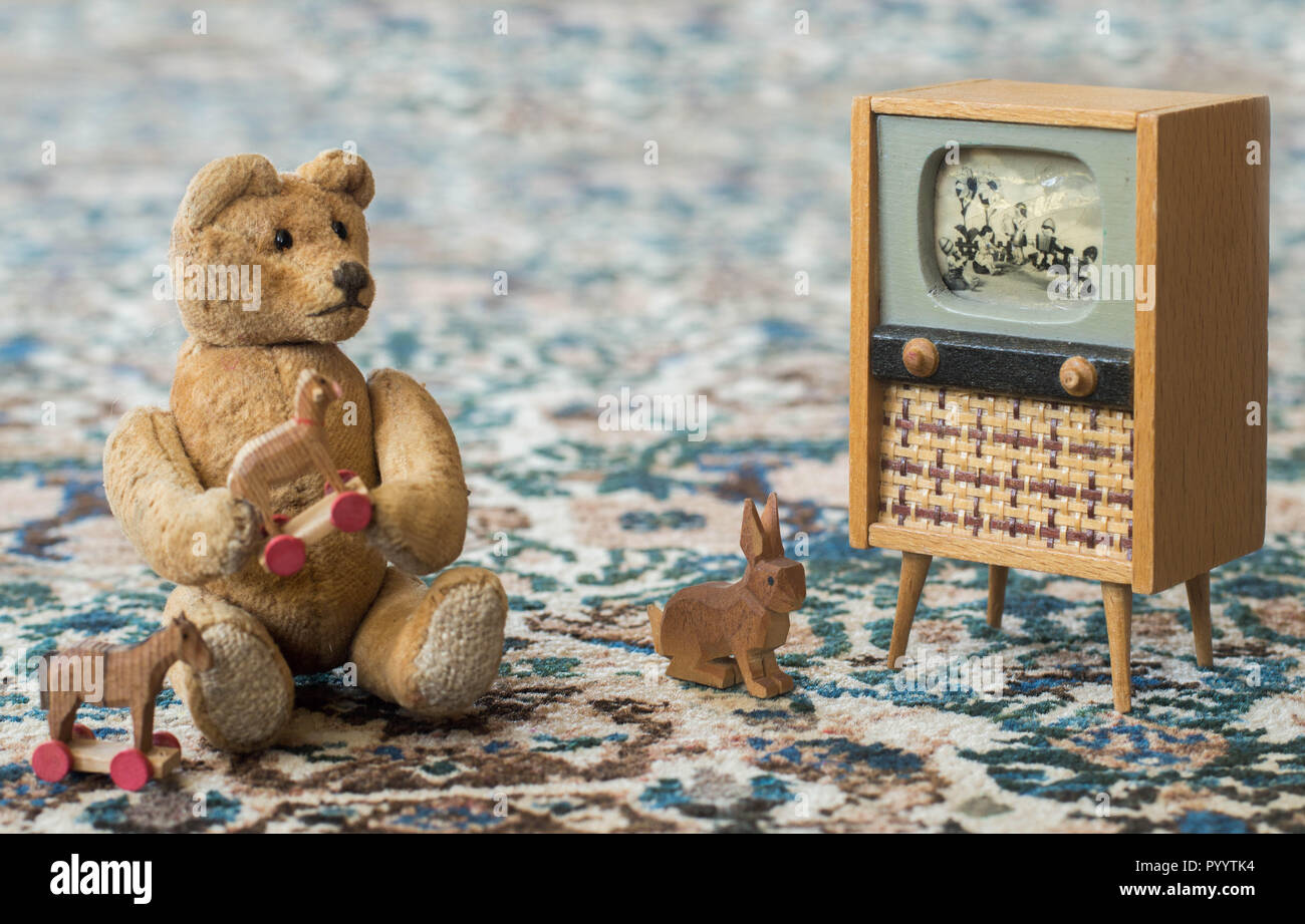 Piccolo orsacchiotto gioca con i giocattoli e guardare la TV come un bambino reale - siede su un tappeto Foto Stock
