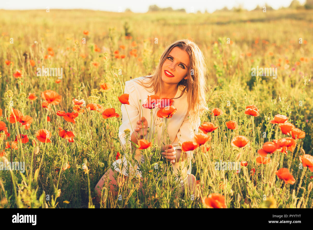 Bella ragazza nel campo con fiori di papavero Foto Stock