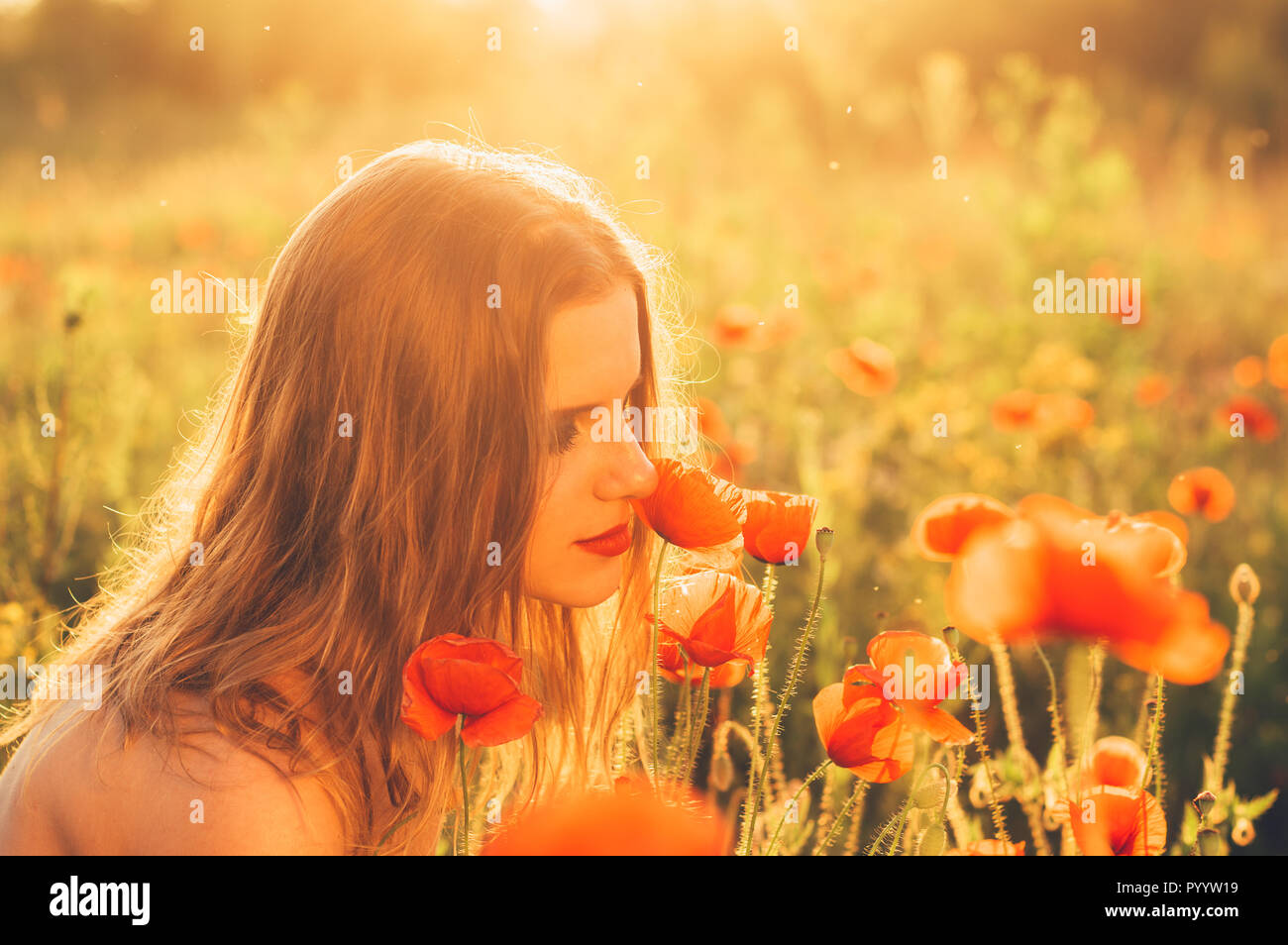 Bella ragazza nel campo con fiori di papavero Foto Stock