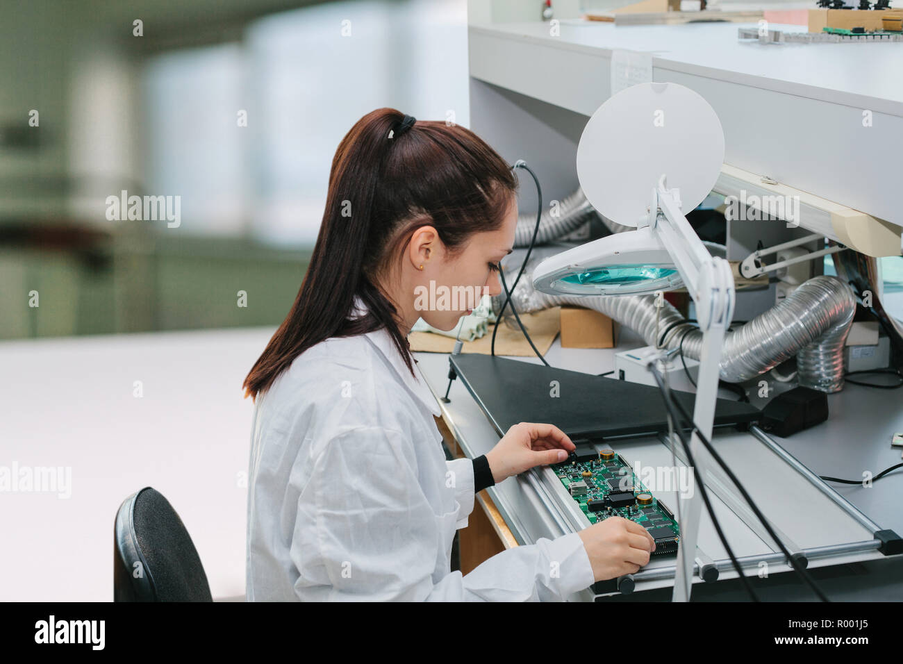Una femmina di tecnico controlla una scheda computer in una fabbrica. Attività professionale. Personale altamente qualificato specialista nel campo del gruppo di computer o Foto Stock