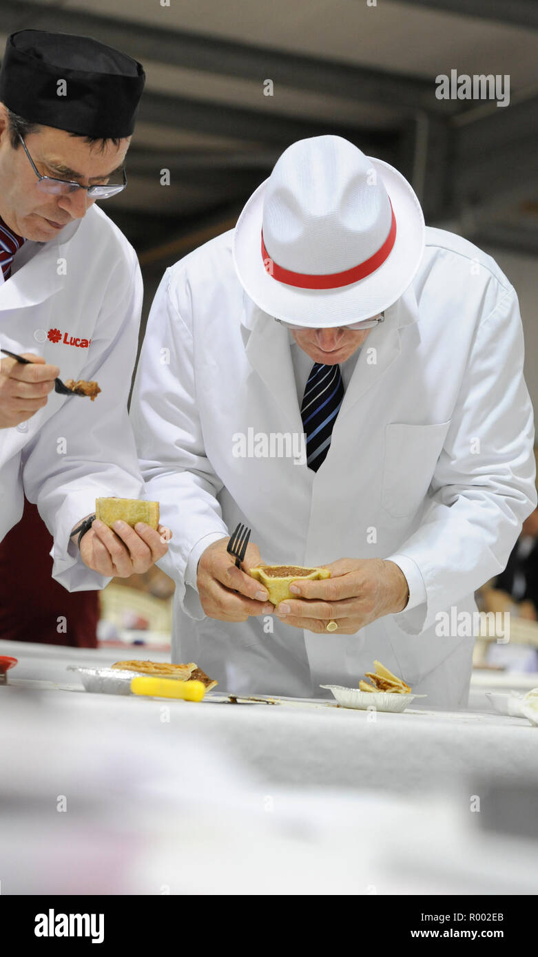 Una coppia di giudici esaminare torte e altre carni produrre ad un concorso regionale per i produttori. Foto Stock