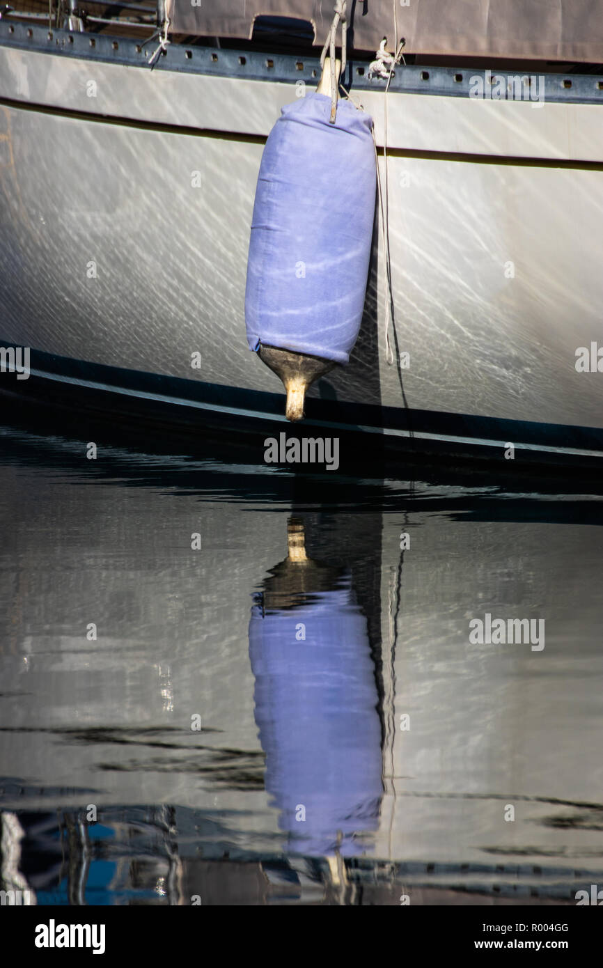Una barca a vela il parafango riflettendo su acque calme Foto Stock