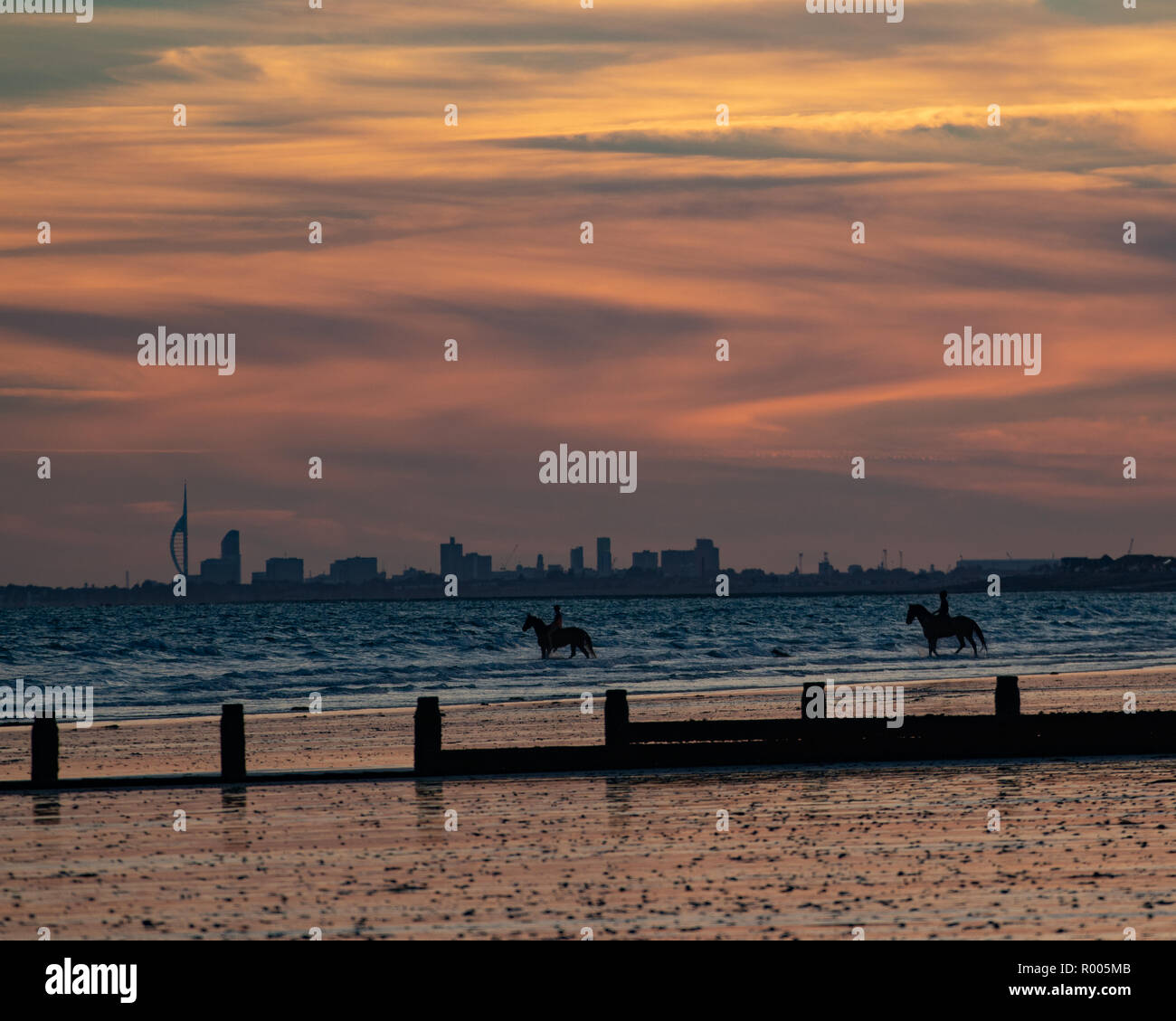 Equitazione su di una spiaggia di sabbia al tramonto Foto Stock