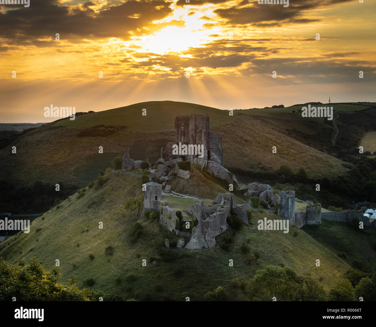 Sunrise over Corfe Castle con i raggi di luce, Dorset, Regno Unito Foto Stock