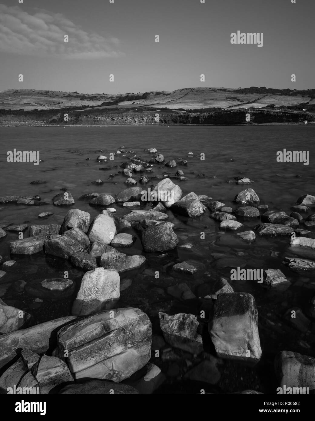 Calmare le acque intorno a rocce in mare con scogliere in background Foto Stock