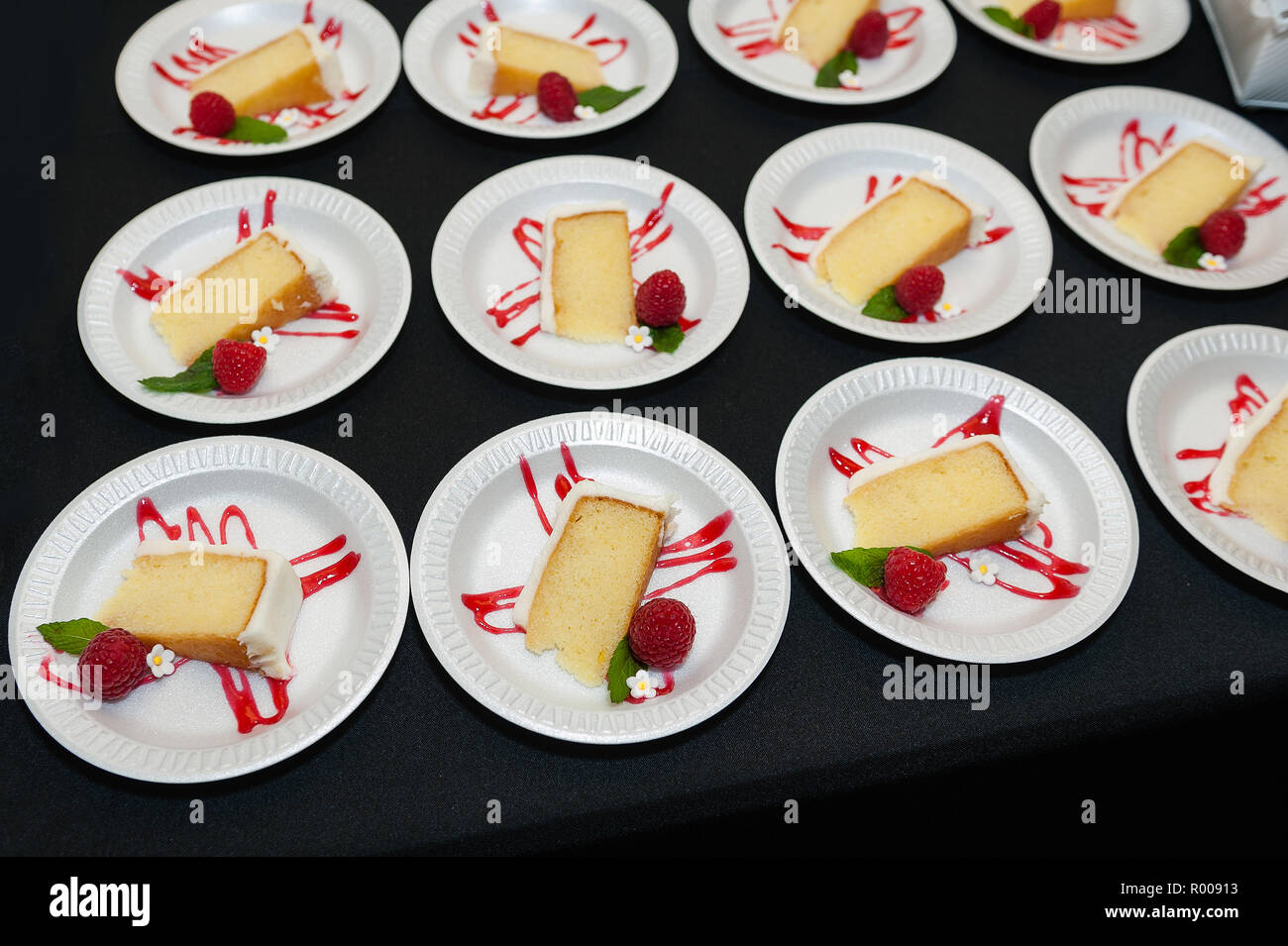 Piastre di giallo la torta con la glassa bianca e lampone guarnire a un ricevimento. Foto Stock