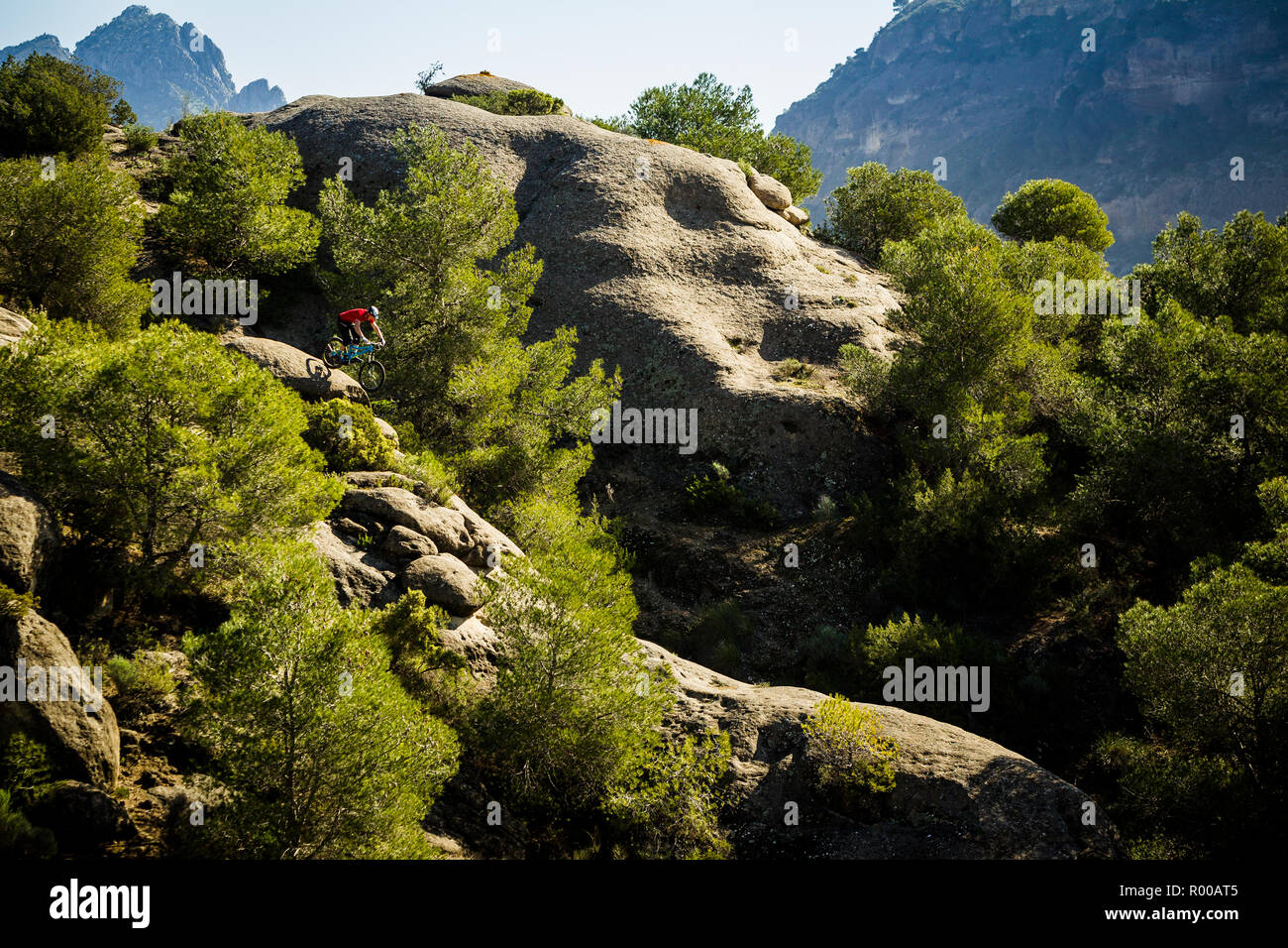 Mountain Biker Chris Akrigg a cavallo su rocce in uno scenario epico Foto Stock