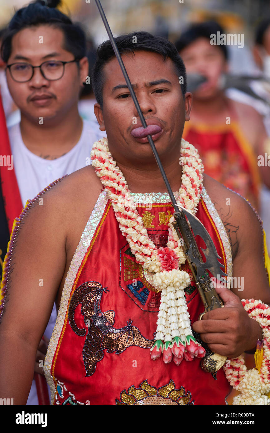 Una processione durante il Festival vegetariano nella città di Phuket, in Thailandia, con un Mah Song o un mezzo spirituale che mostra la sua lingua trafugata da un'asta di ferro Foto Stock