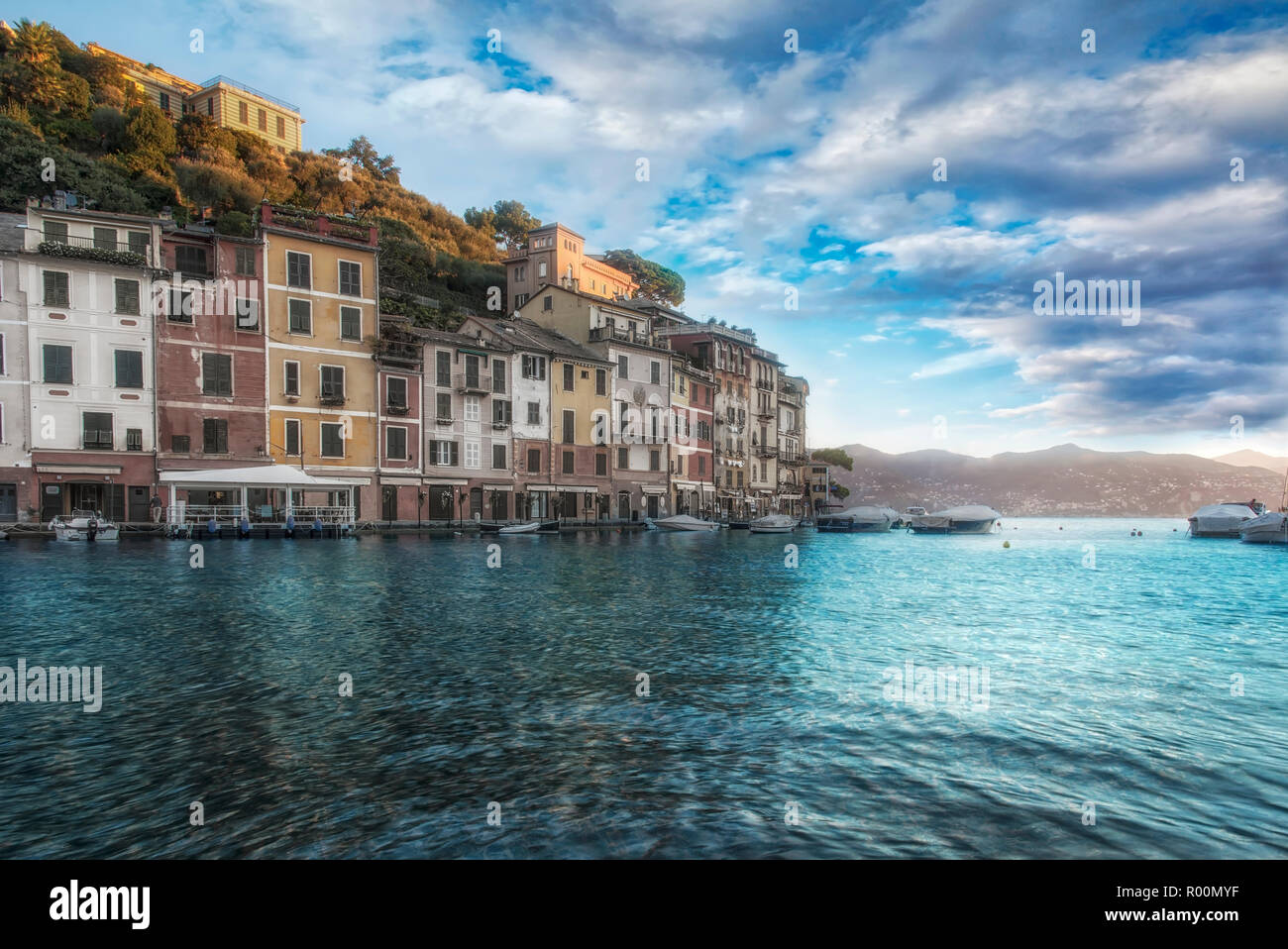 Rosa pittoresca vista al tramonto di Portofino, Italia con drammatica nuvole sopra un calmo mare ligure e colorate case sul lungomare Foto Stock