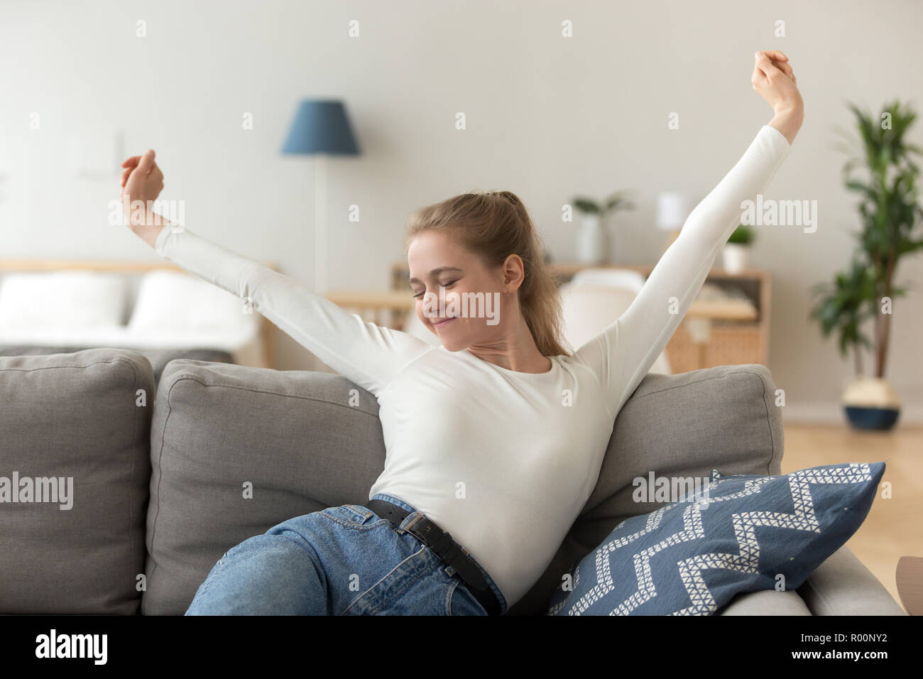 Soddisfatto ragazza seduta sul lettino relax in casa Foto Stock
