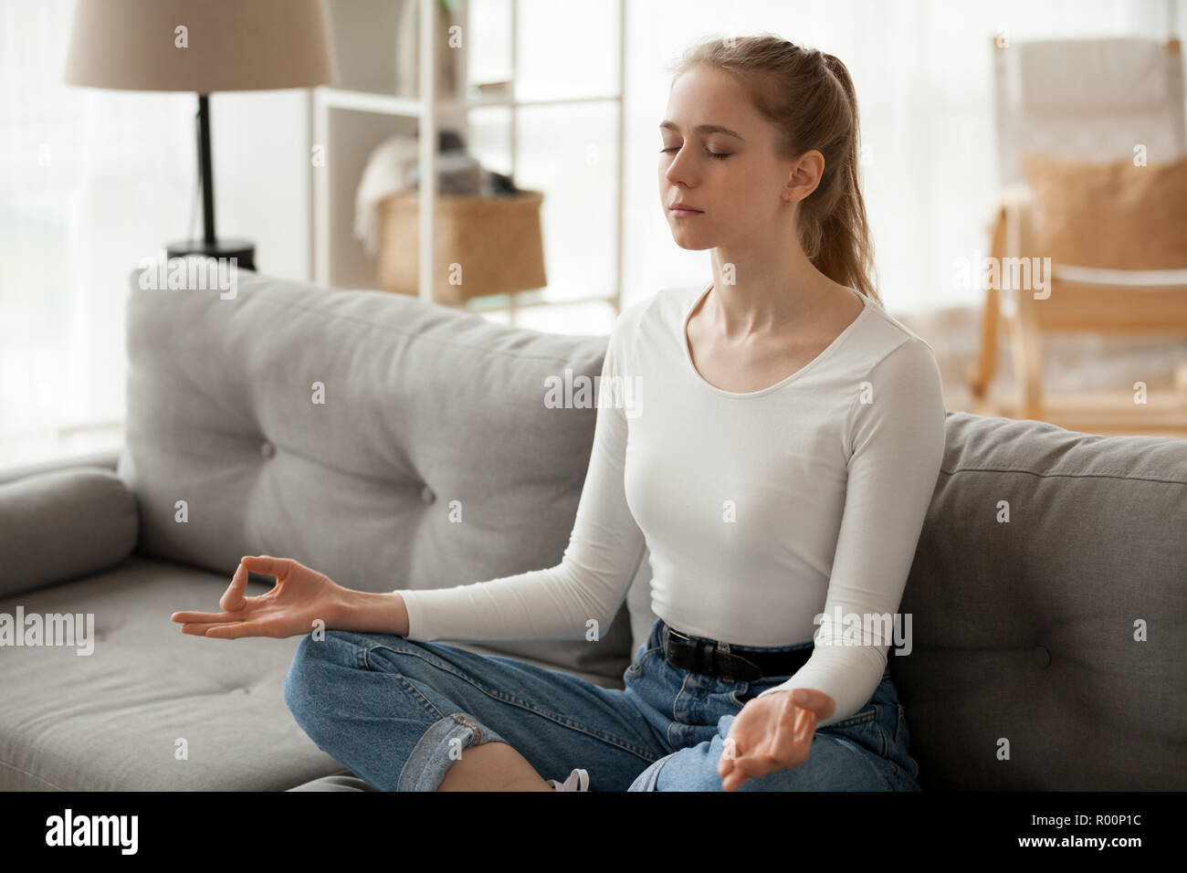 Donna meditando seduto sul divano di casa Foto Stock