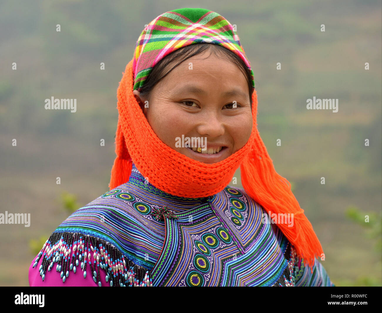Giovane vietnamita H'mongs appartenenti a minoranze hill-tribe donna con un dente d'oro indossa scialle arancione e tradizionale ricamato H'mongs costumi in blu. Foto Stock