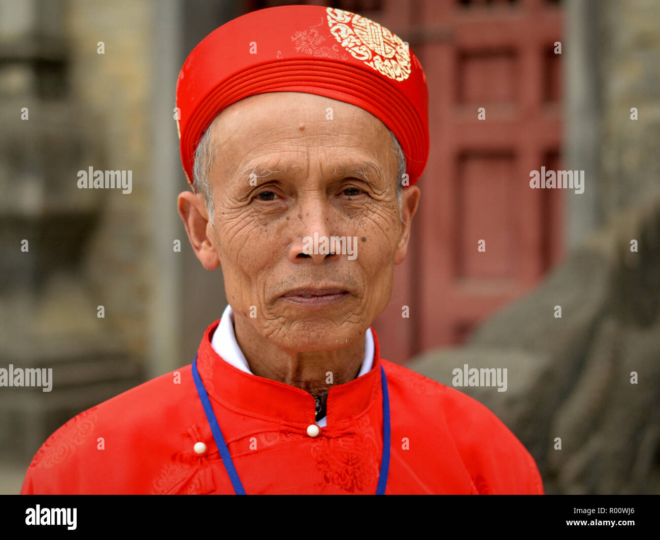 Gli anziani della comunità vietnamita leader indossa un rosso tradizionale costume taoista durante la Bac Ha Festival tempio. Foto Stock