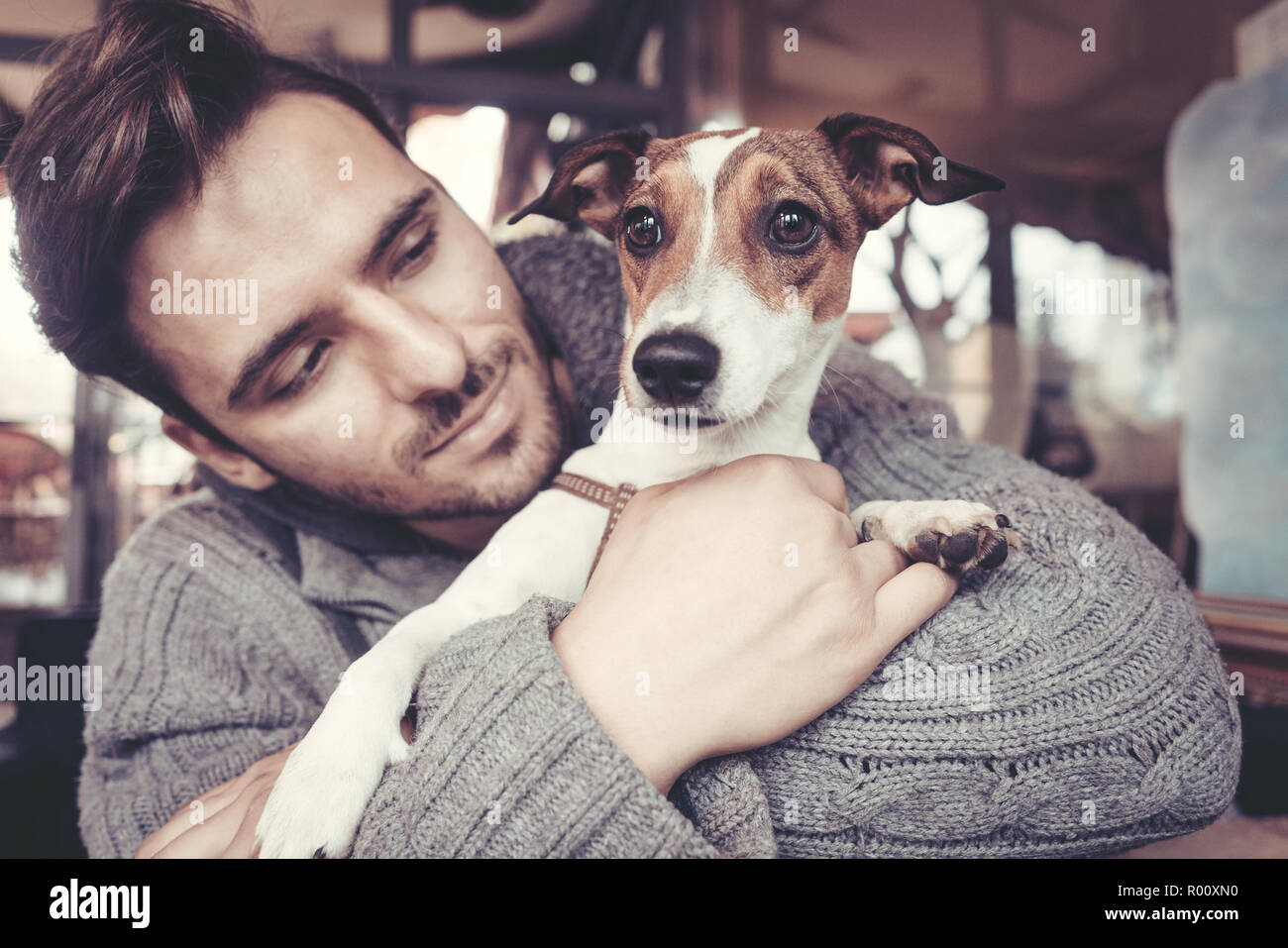 Cuddling l uomo con il suo cane in inverno Foto Stock