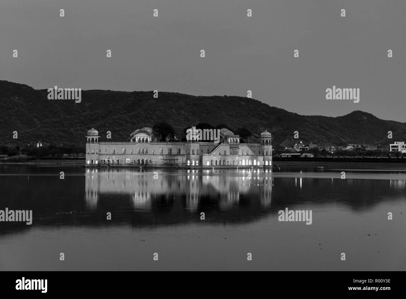 Illuminata Jal Mahal Palace di notte a Jaipur, India. Punto di riferimento popolare circondata dall'acqua. Le montagne sullo sfondo. In bianco e nero Foto Stock