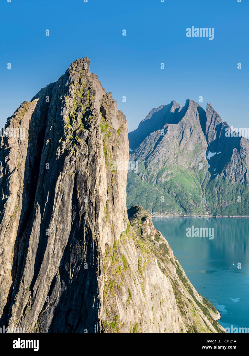Mountain Segla visto dalla montagna Hesten, ripida scogliera, picco Breidtinden nel retro, piccola imbarcazione a vela sulla calma vedere, isola Senja, Troms, Norvegia Foto Stock