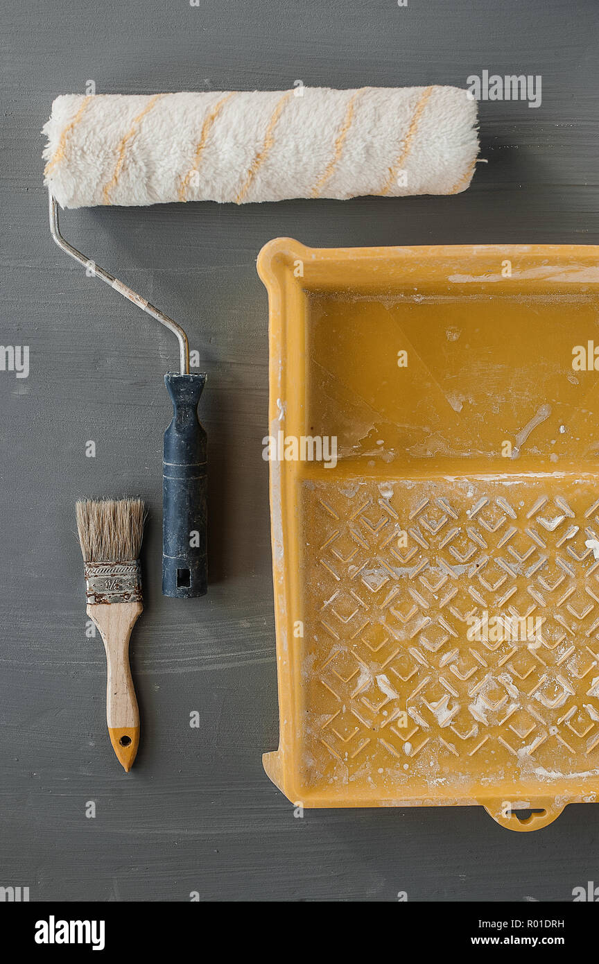 L'oggetto strumenti del lavoratore di vernice concetto, vernice spazzola a rullo e vernice bianco colore utilizzato nel vassoio di plastica. Selettiva e soft focus per lo sfondo. Foto Stock