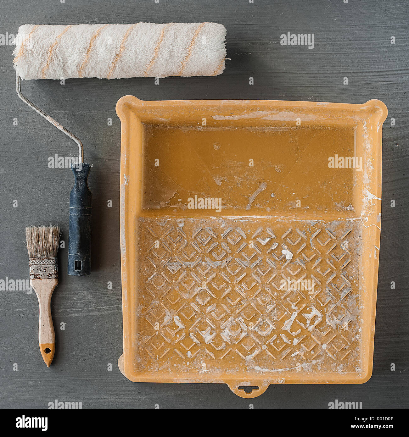 L'oggetto strumenti del lavoratore di vernice concetto, vernice spazzola a rullo e vernice bianco colore utilizzato nel vassoio di plastica. Selettiva e soft focus per lo sfondo. Foto Stock