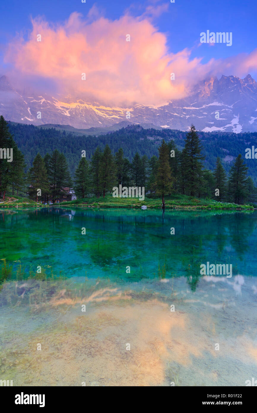 Il Cloud illuminata con i colori dell'alba è riflessa nel Lago Blu. Il lago blu, Cervinia, Valtournanche, Valle d'Aosta, Italia, Europa Foto Stock