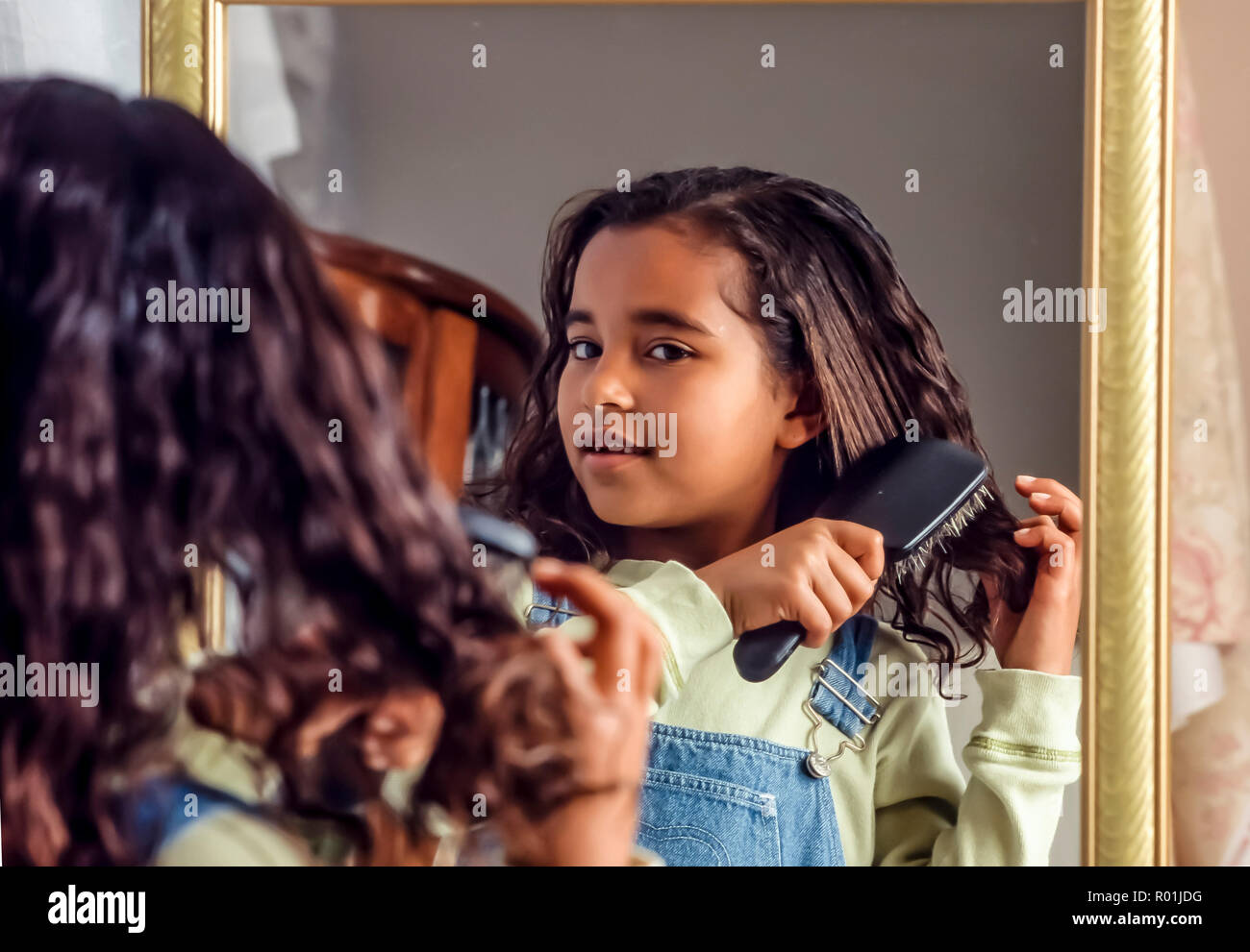 Giovani 7-8 anno vecchia ragazza spazzolare i capelli mentre guardando nello specchio. Ottenere pronto per la scuola. © Myrleen Pearson .......Ferguson Cate Foto Stock