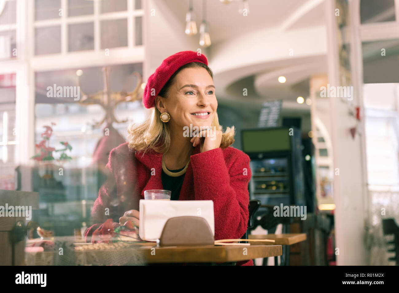 Elegante sentimento donna seduta straordinaria in panetteria e cercando nella finestra Foto Stock