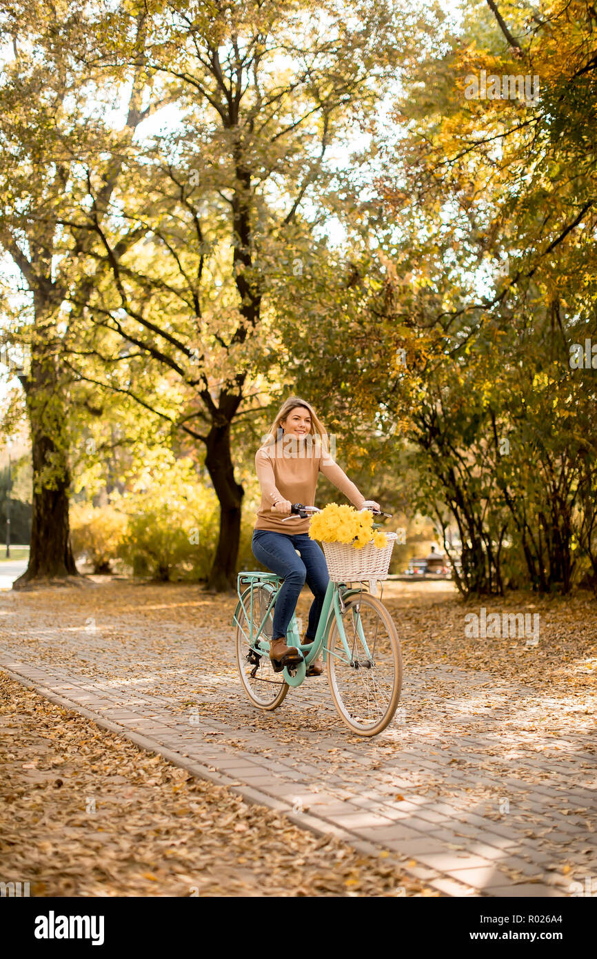 Felice donna attiva Bicicletta Equitazione in autunno dorato park Foto Stock