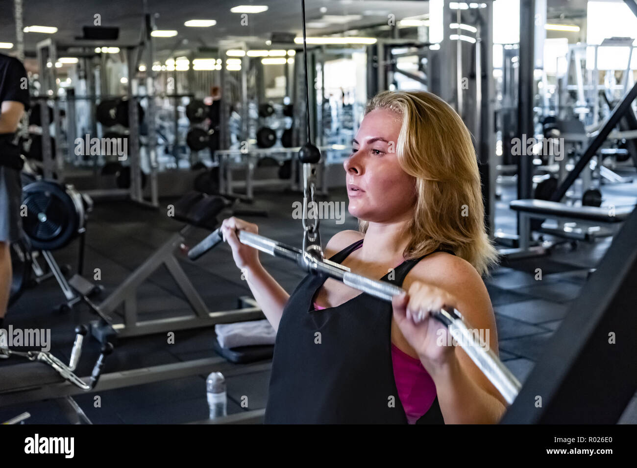 Montare la giovane donna presso la palestra pulldown facendo esercizio con il peso della macchina. Atleta femminile in una sala fitness che lavora fuori con puleggia ponderata macchina Foto Stock