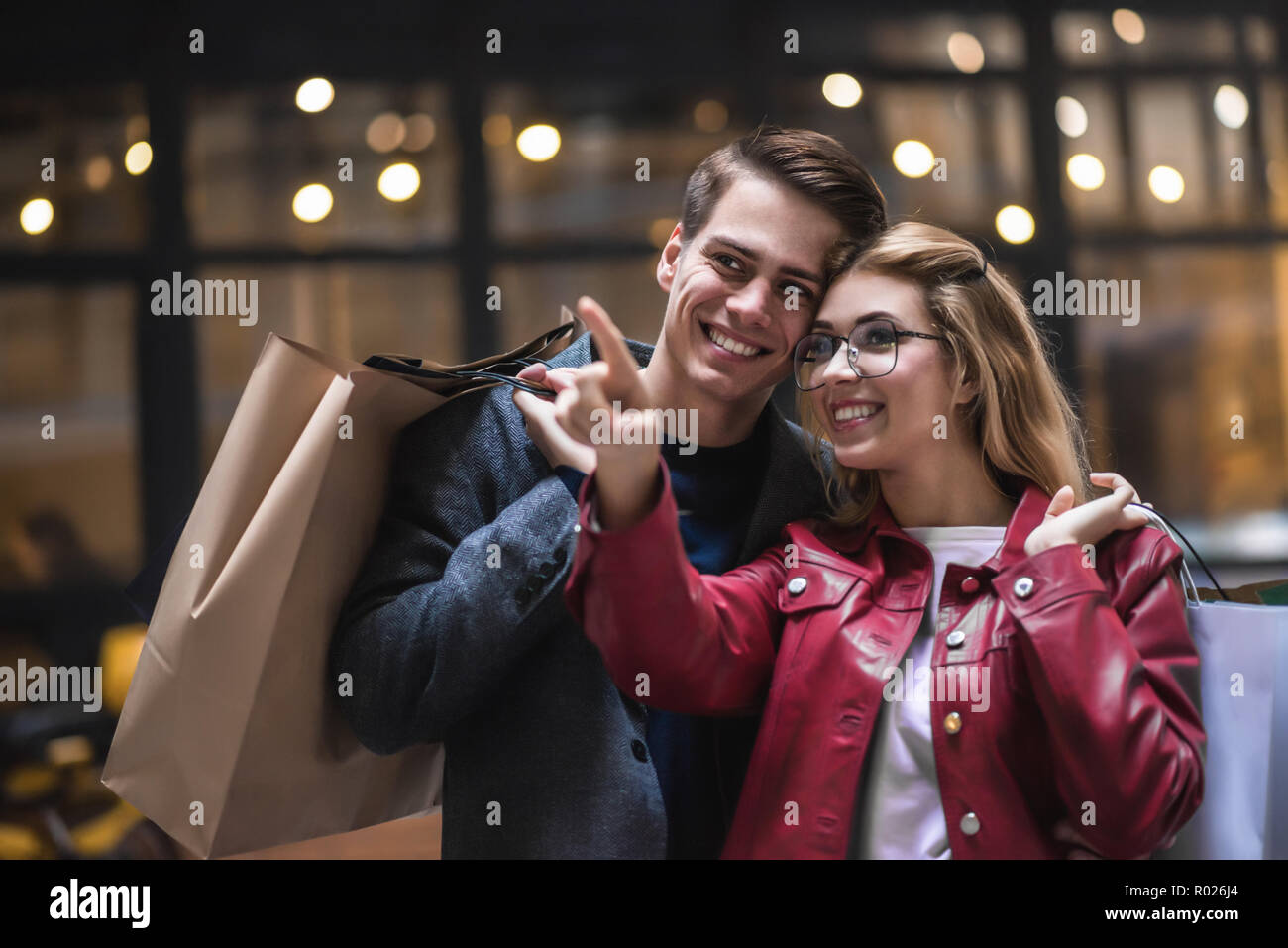 Bella giovane con le borse della spesa è di parlare e sorridere mentre facendo shopping nel centro commerciale focus sulla donna Foto Stock