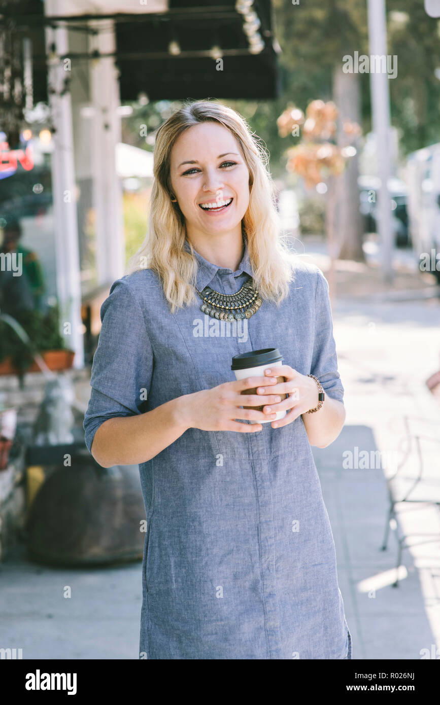 Giovane ragazza millenaria con un sorriso e di bere il caffè Foto Stock