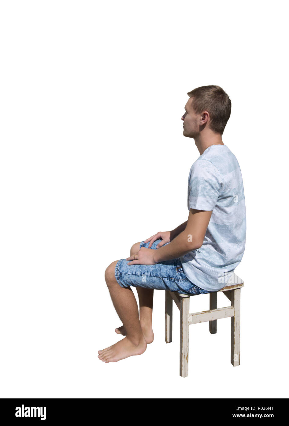 Vista laterale a piena lunghezza Ritratto di pensieroso giovane uomo seduto su una sedia e guardando lontano isolate su sfondo bianco. Foto Stock