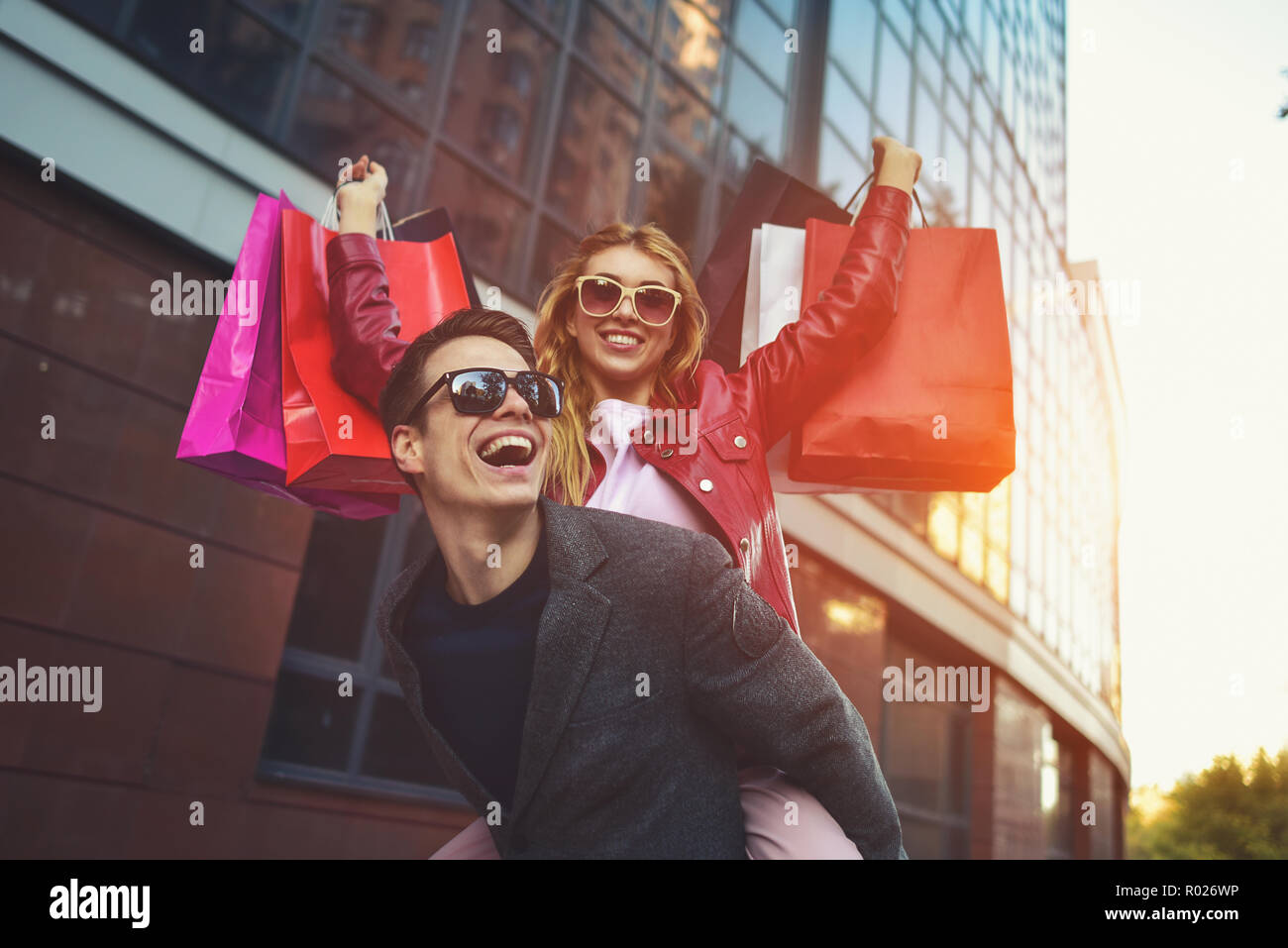 Coppia felice shopping insieme e divertirsi. Ragazzo portando la sua fidanzata sulla strada-ferrovia. Foto Stock