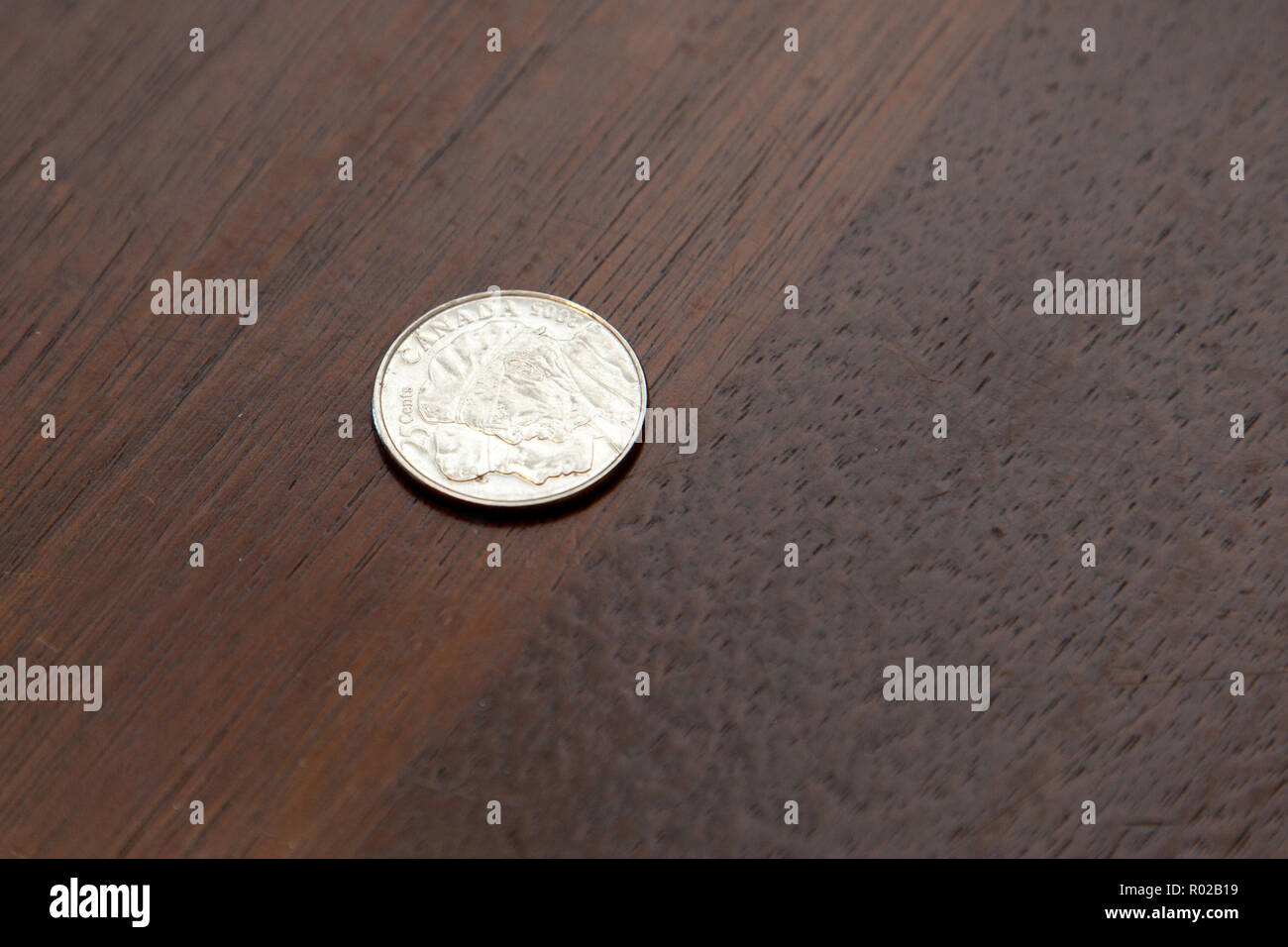 Un singolo metallo 25 cent si siede su un tavolo di legno circondato da spazio di copia Foto Stock