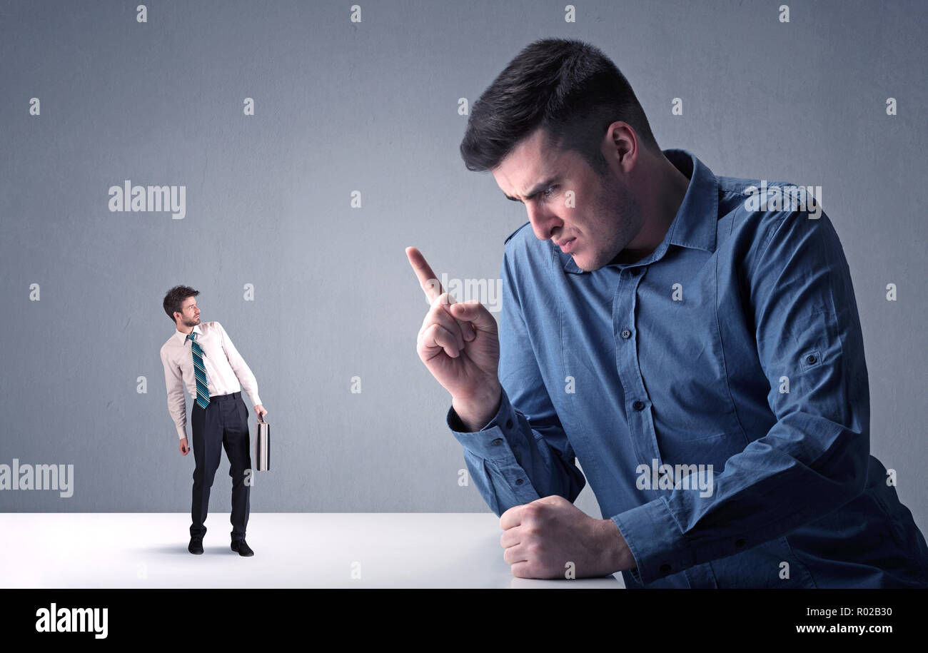 Giovane imprenditore professionale essendo arrabbiato con un altro imprenditore in miniatura Foto Stock